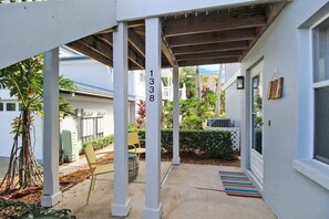 Uma varanda coberta com piso de concreto, colunas brancas e o número 1338 na parede.