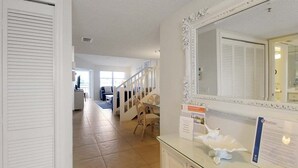 A hallway with a glass display case, a white door, and a staircase leading to another room. - Bayfront Siesta Key condo with amazing views - GBB 1391 (Siesta Key)