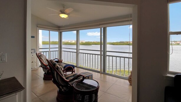 A room with a view of a body of water, a ceiling fan, and a dining area with chairs and a table. - Bayfront Siesta Key condo with amazing views - GBB 1391 (Siesta Key)