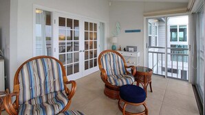 A spacious balcony with two wicker chairs and a small table, white walls, and a view of the outside. - Bayfront Siesta Key condo with amazing views - GBB 1391 (Siesta Key)