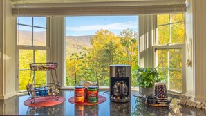 Un comptoir de cuisine donnant sur le paysage automnal grâce à de grandes fenêtres.