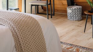 Una habitación acogedora con techo inclinado, un escritorio de madera, una silla, una cama y una planta en maceta.
