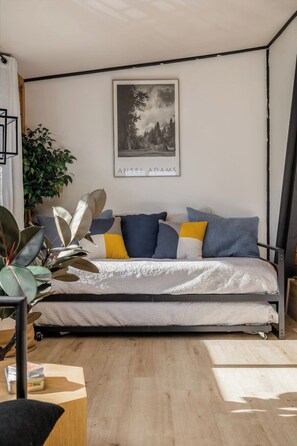 A modern bedroom with a bed, a large framed picture on the wall, and a potted plant.