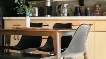 Une cuisine moderne avec des meubles en bois, une table à manger avec des chaises et des luminaires suspendus.