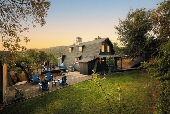A two-story house with a deck, outdoor seating, and a staircase leading to a second level.