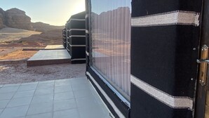 A building with a large black and white striped awning, a tiled floor, and a view of a desert landscape. - Wadi Rum Rose camP (Wadi Rum)
