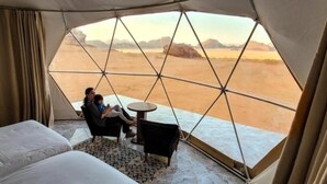 A tent with a geometric window design, a bed, a small table, and a chair. - Wadi Rum Rose camP (Wadi Rum)