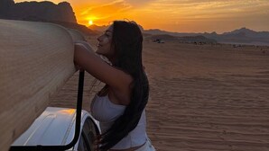 A desert landscape with a sunset, a vehicle, and a person leaning on the vehicle. - Wadi Rum Rose camP (Wadi Rum)