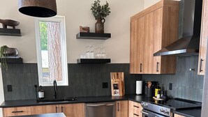 Eine moderne Küche mit Holzausbau, einer schwarzen Arbeitsplatte, einem eingebauten Backofen und einem Edelstahl-Geschirrspüler.