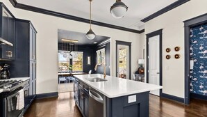 A modern kitchen with dark cabinetry, a large island, and pendant lighting. - Lockeland Luxe｜Walk to 5 Points｜2 mi to Broadway (Nashville)