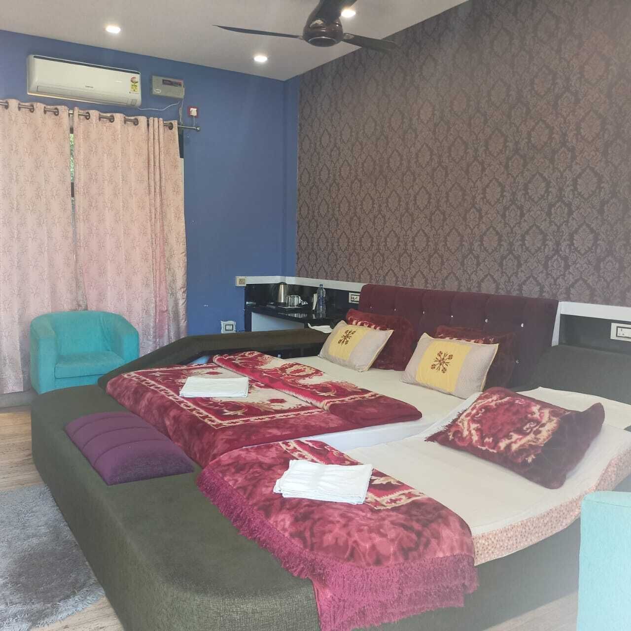 Een slaapkamer met een groot bed, een plafondventilator, een airconditioning en een klein bureau met stoel.