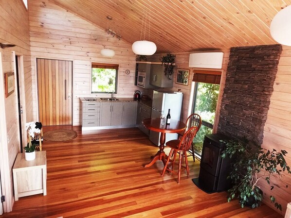 A wooden cabin interior with a kitchen, dining area, and fireplace.