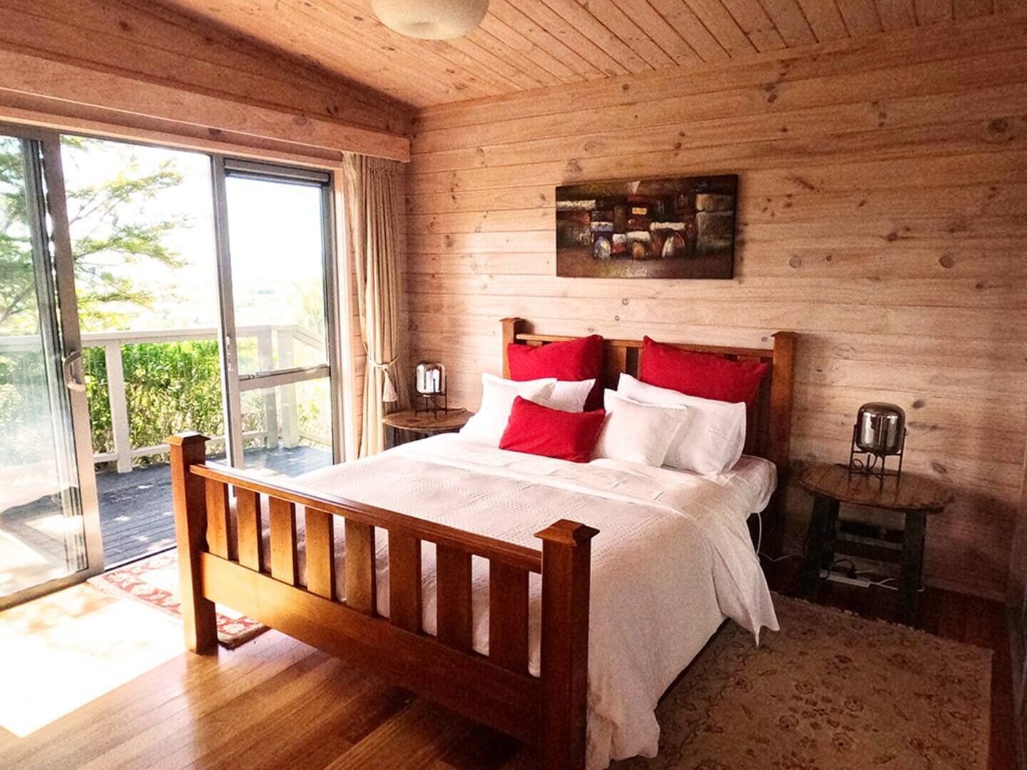 A wooden-paneled bedroom with a large bed, a small table, and a chair.