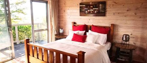 A wooden-paneled bedroom with a large bed, a small table, and a chair.