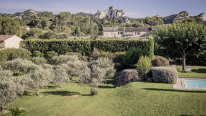 A villa with a swimming pool, surrounded by well-maintained gardens and olive trees.