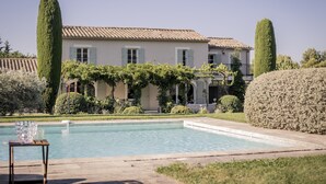 A pool with a clear view of a building with a tiled roof and a well-maintained garden.