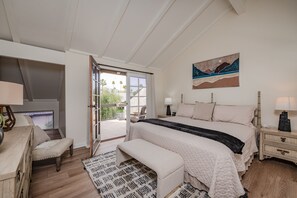 Une chambre avec un grand lit, un bureau et une chaise. Une porte-fenêtre coulissante donne accès à un espace extérieur.