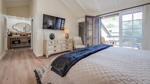 A bedroom with a large bed, a TV, a dresser, and a window with a view of the outdoors. - Hidden Gem - Spacious and Gorgeous Getaway by the Pool  (Palm Springs)