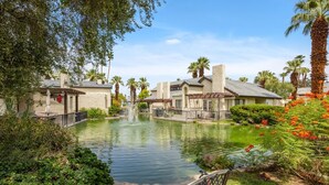 A serene courtyard with a central pond, surrounded by palm trees and lush greenery. - Hidden Gem - Spacious and Gorgeous Getaway by the Pool  (Palm Springs)