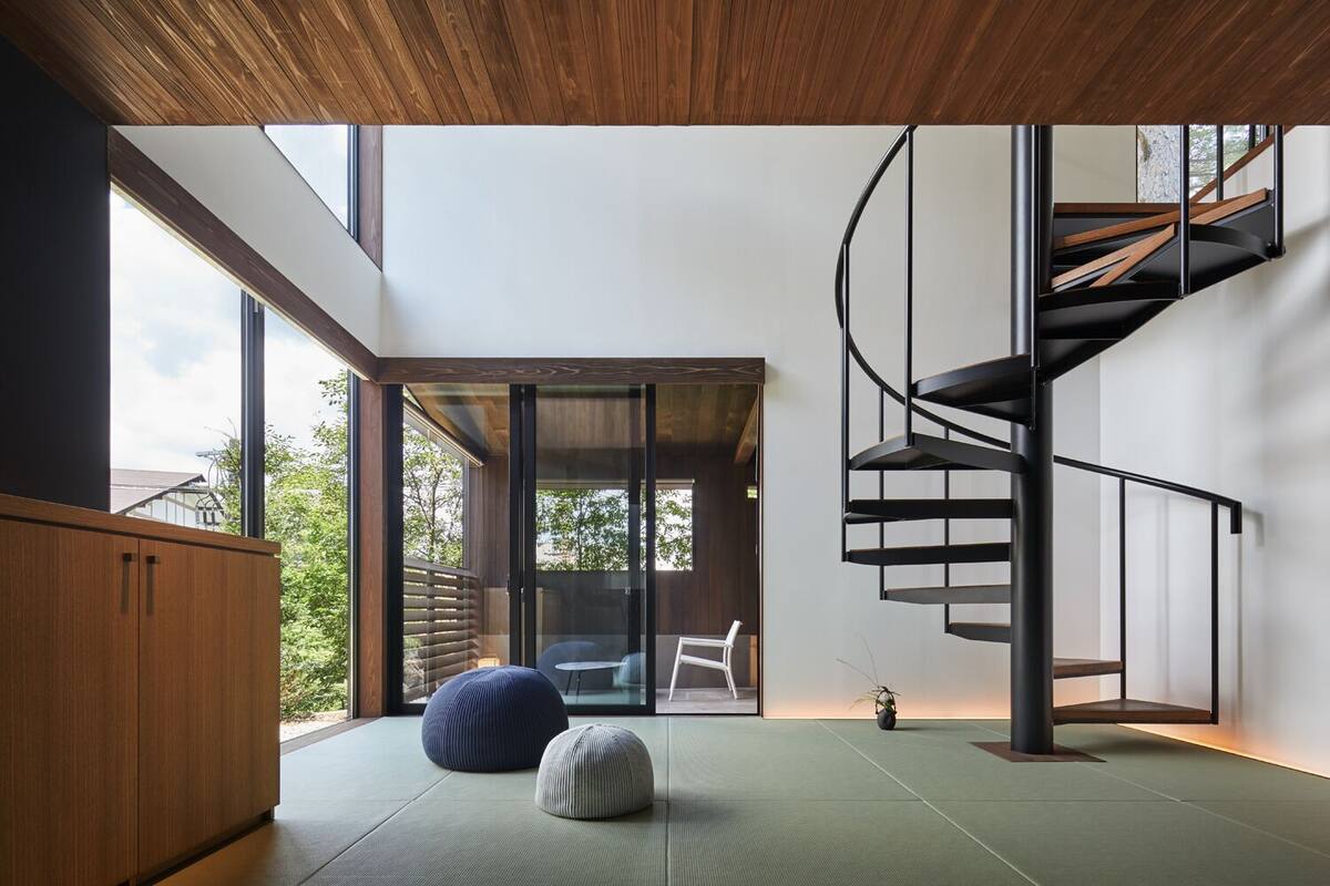 A modern interior with a spiral staircase, tatami mats, and a view of the outdoors.