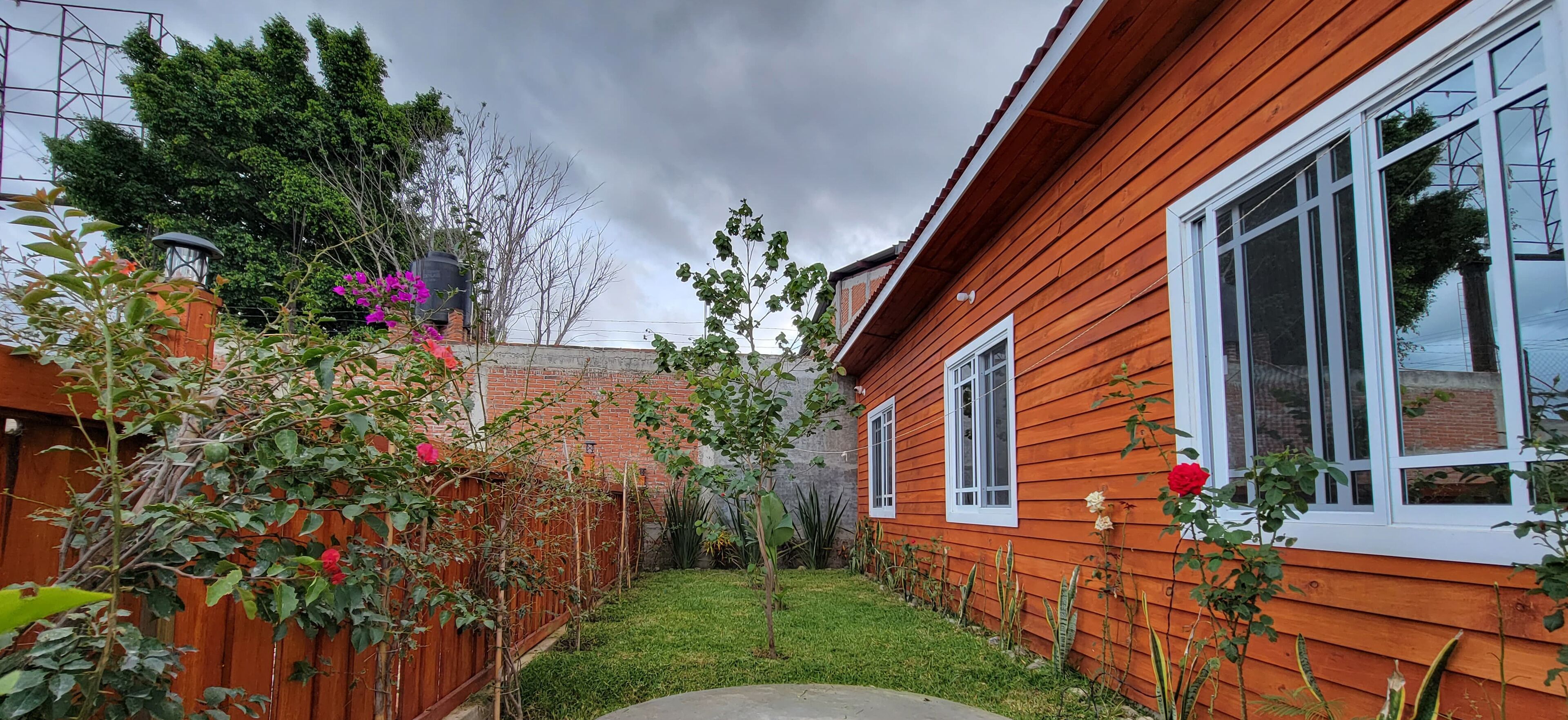 A wooden house with a brick wall and a small garden.
