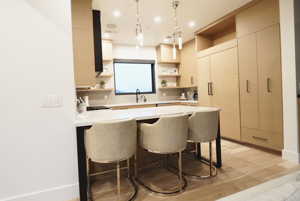 A modern kitchen with a central island, bar stools, wooden cabinets, and pendant lighting. - Retreat At The Ridge- Free Shuttle Out/Ski In (Park City)