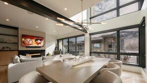 Una sala de estar moderna con un ventanal grande, chimenea y comedor.