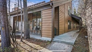 Una casa moderna con un porche cubierto y un pequeño espacio exterior para sentarse.