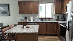 Eine moderne Küche mit Granit-Arbeitsplatten, Holzschränken, einer zentralen Kochinsel und integrierten Geräten.