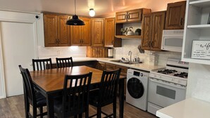 Una cocina moderna con armarios de madera, una mesa de comedor, sillas, lavadora, estufa y microondas.