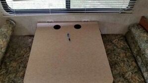 Un petit espace clos avec des sièges, doté d’une surface plane et de deux ouvertures circulaires, probablement destinées à la ventilation, dans une pièce dont le revêtement mural présente un motif décoratif.