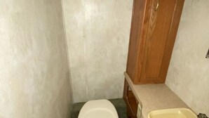 Une petite salle de bain avec des toilettes, un lavabo et un meuble en bois.