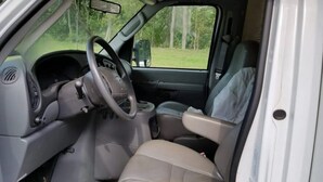 L'intérieur d'un véhicule, avec un volant, des sièges de couleur beige et un tableau de bord.