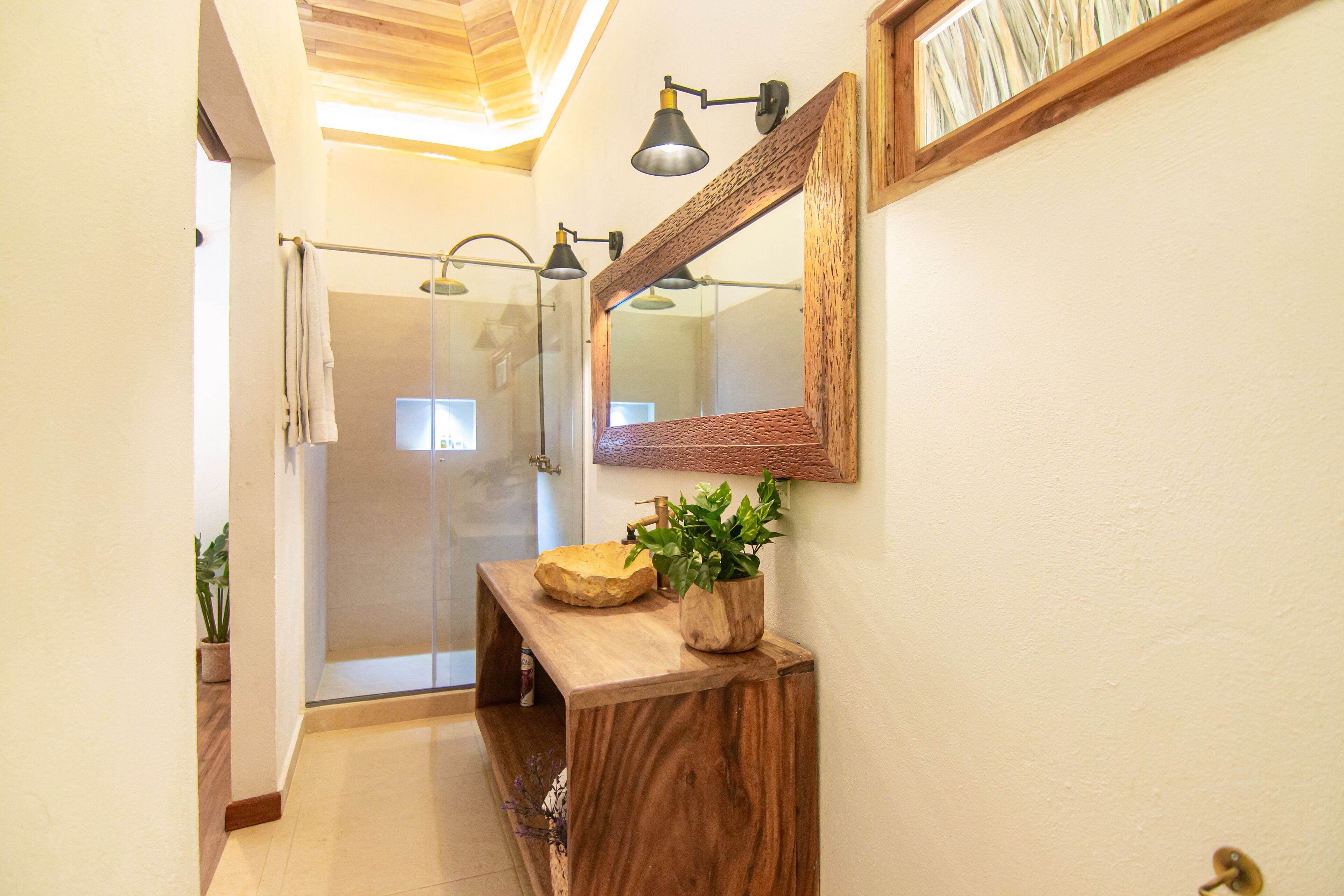 Une salle de bain avec un meuble-lavabo en bois, un grand miroir et un espace douche.