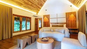 A modern living room with a large sofa, a wooden coffee table, and a unique hanging light fixture. - Tewimake Hotel  (Santa Marta)