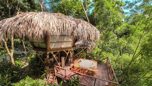 A treehouse with a thatched roof, wooden deck, and a small table. - Tewimake Hotel  (Santa Marta)