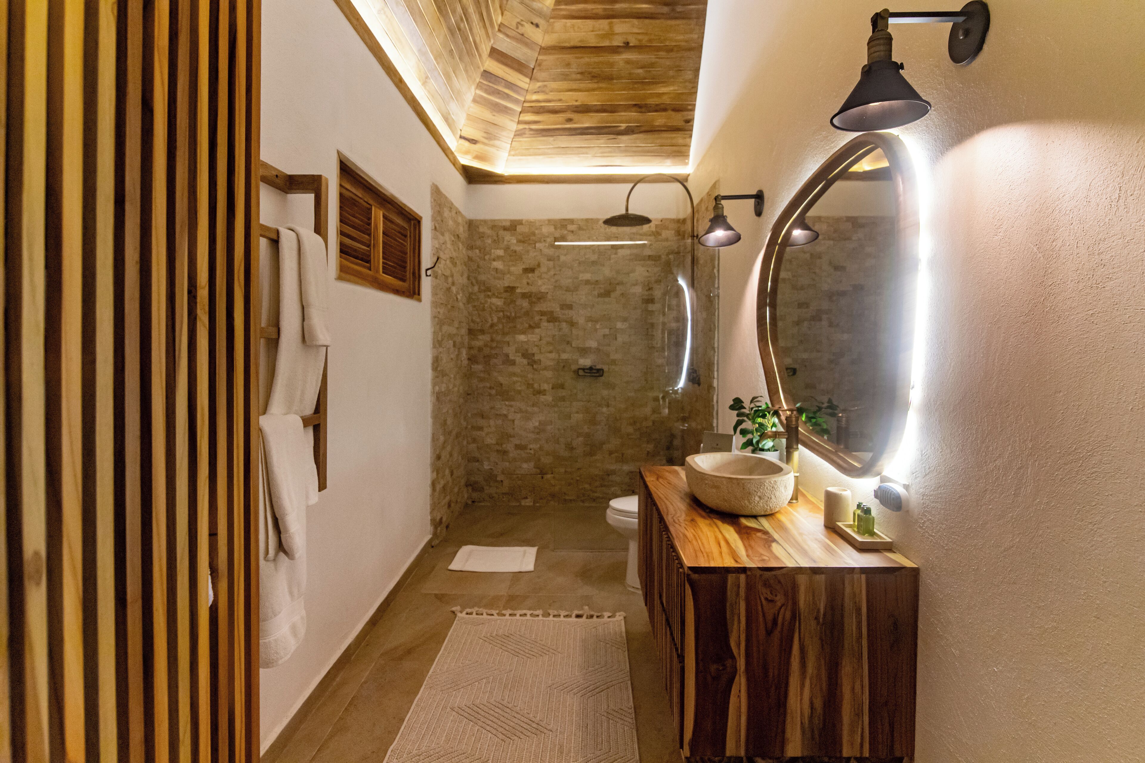 A bathroom with a wooden vanity, a large mirror, and a shower area.