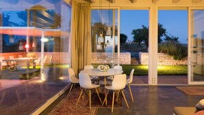 A modern dining area with a glass wall, a stone wall, and a view of the outdoors.
