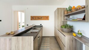 A modern kitchen with wooden cabinetry, a central island, and a hanging wooden artwork.