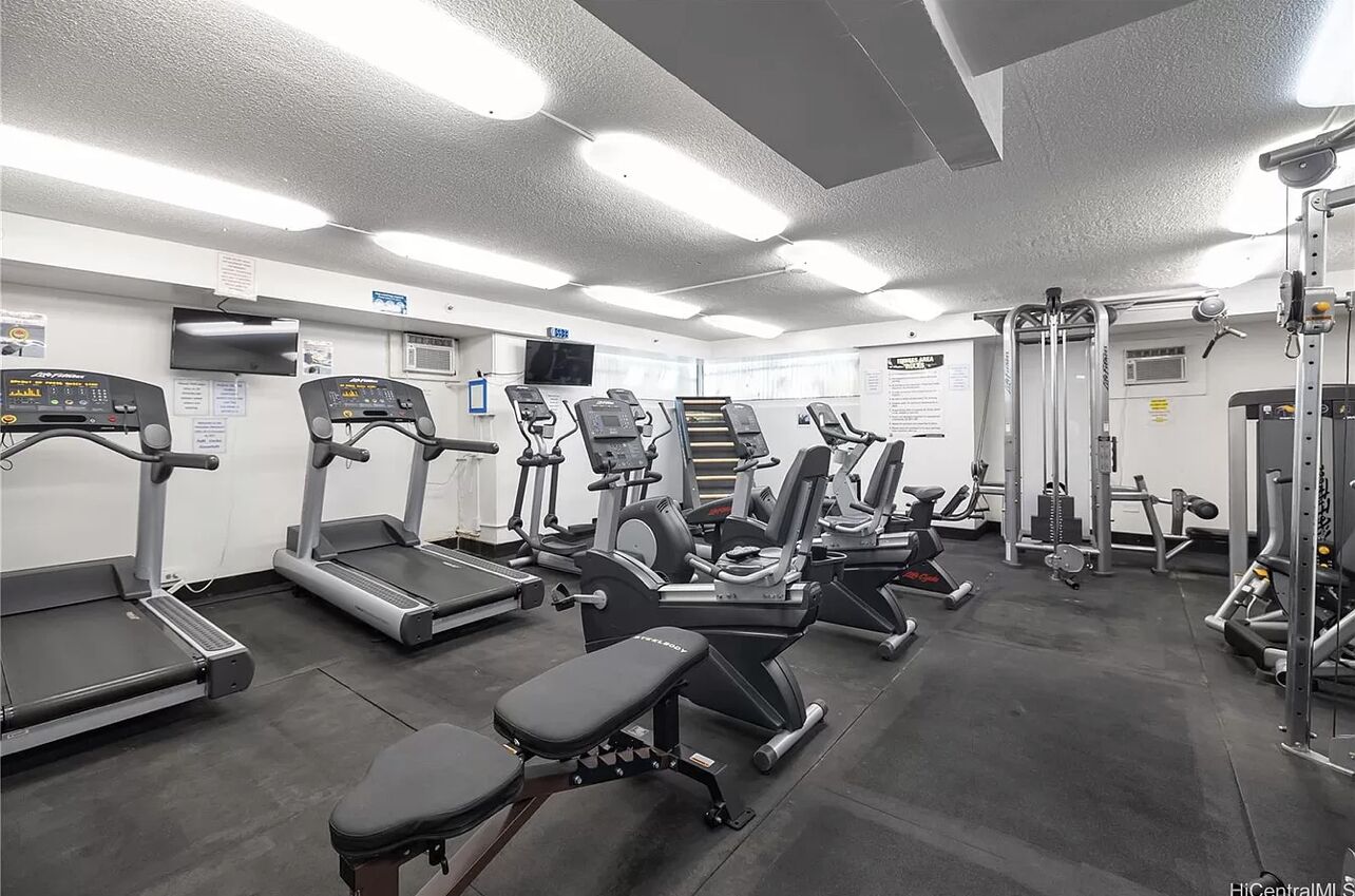 A gym with treadmills, elliptical machines, and weightlifting equipment.