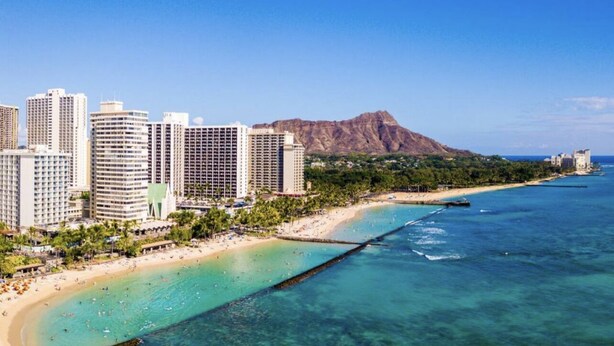 A coastal cityscape with high-rise hotels, a beach, and a mountain in the background. - Cozy condo at Hawaiian monarch- no resort fee, free parking, near beaches, shop (Honolulu)