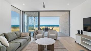 A modern living room with a large window, a sofa, a coffee table, and a TV.
