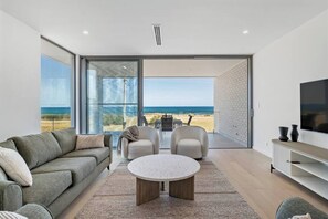 Una sala de estar moderna con un ventanal grande, un sofá, una mesa de centro y un televisor.