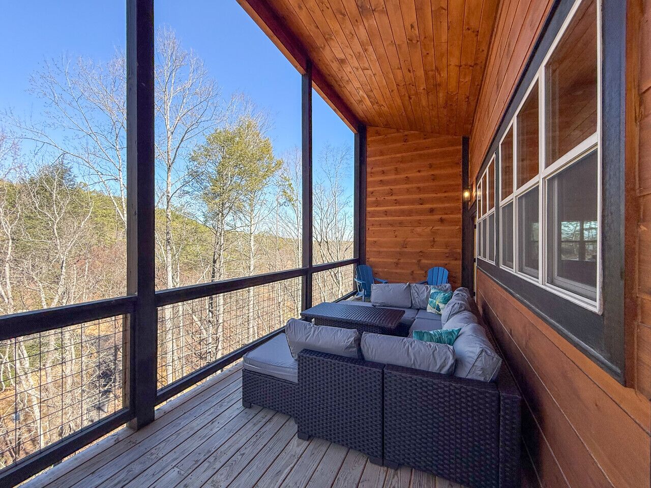 A wooden deck with wicker furniture and a view of trees.