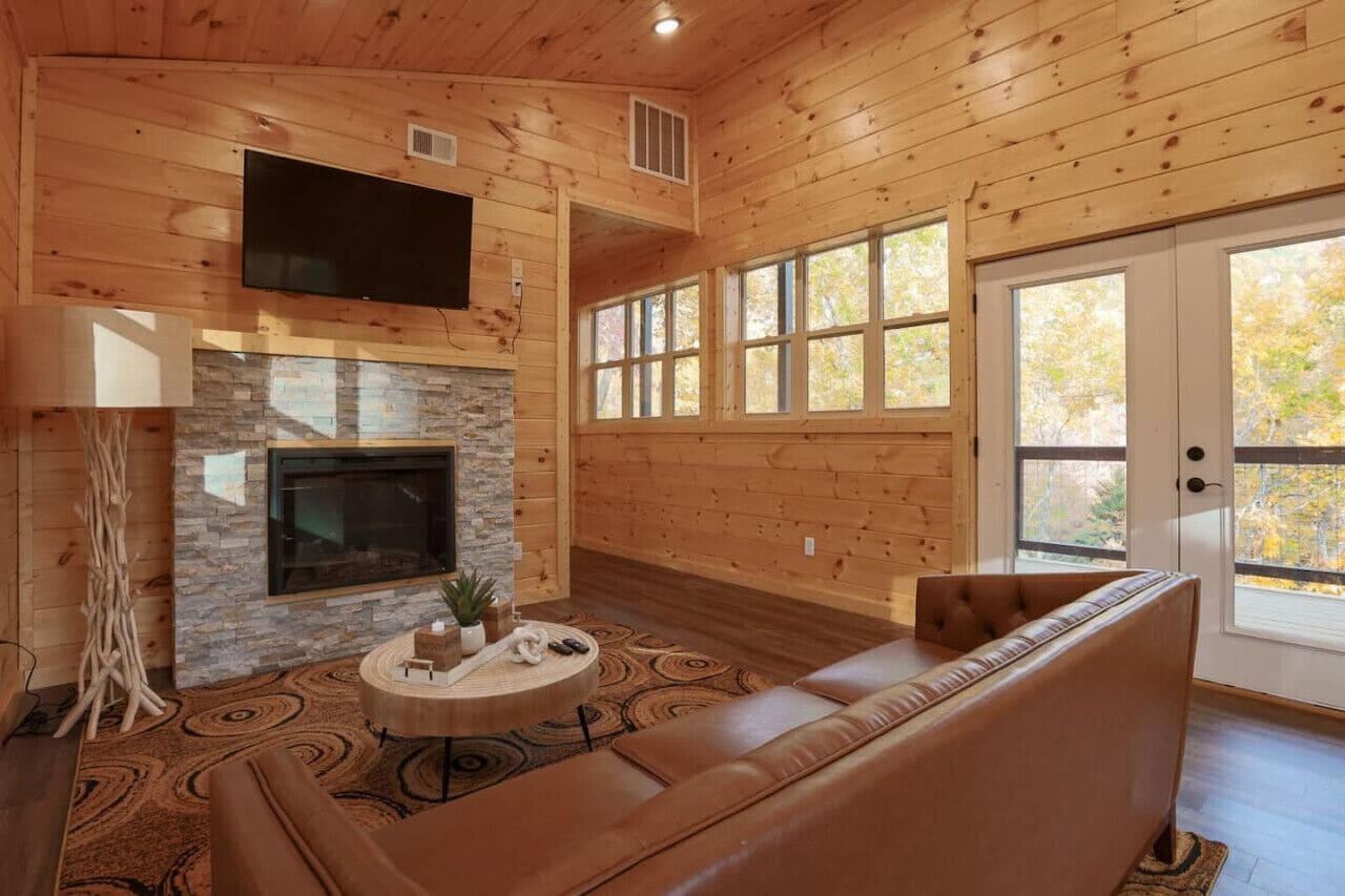 A wooden interior with a fireplace, a sofa, and a television.