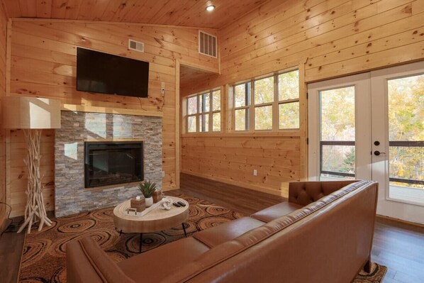 A wooden interior with a fireplace, a sofa, and a television.