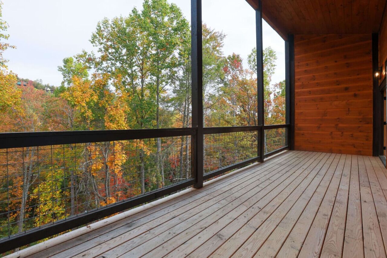 Una terraza de madera con vistas a árboles otoñales.