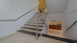A modern staircase with metal railings and black steps leading to a lower level. - Treebo Central (Thrissur)