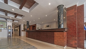 A reception area with a brick counter, a large column, and a clock on the wall. - Treebo Central (Thrissur)