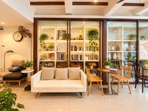 A modern living room with a sofa, chairs, a small table, a bookshelf, and a clock on the wall. - Samer Boutique Stay (Bangkok)